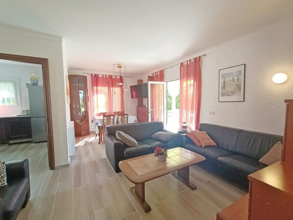 A living room with a sofa, coffee table, and dining area with a TV.