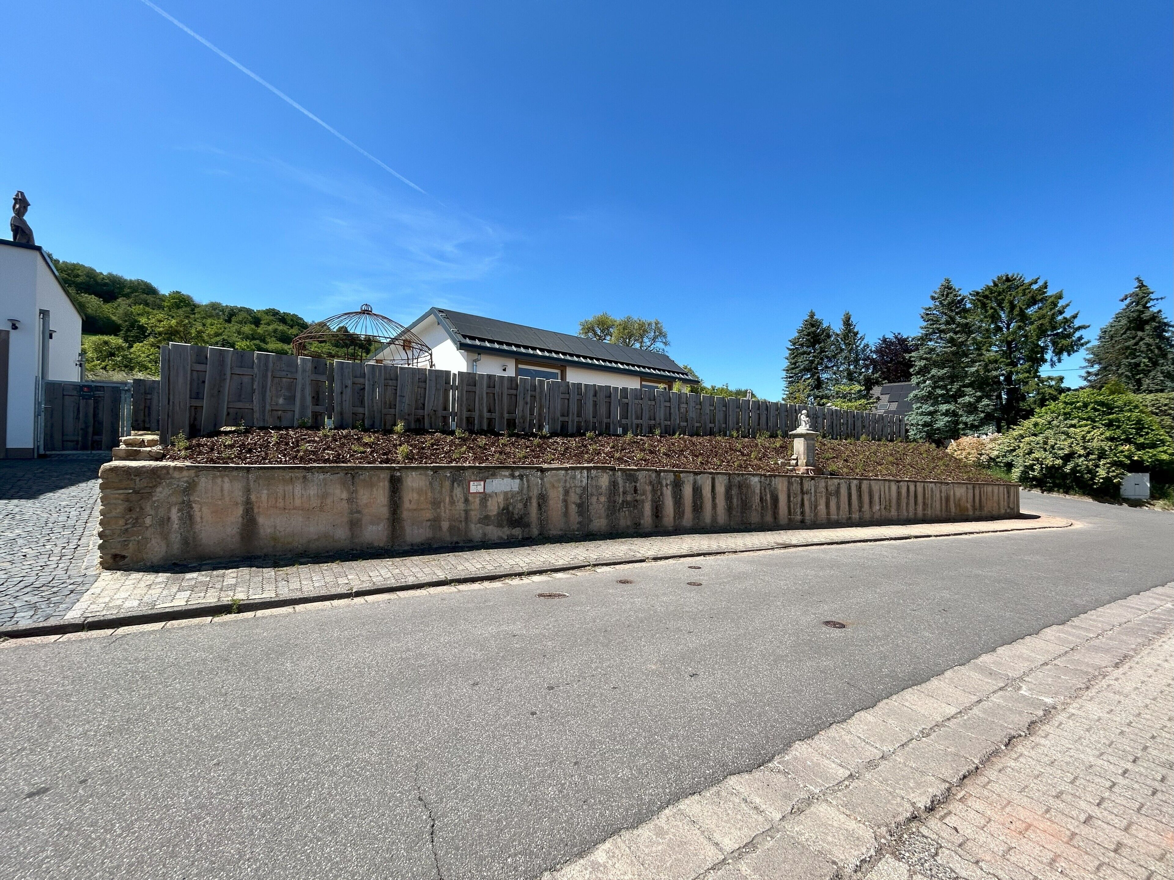 Une route asphaltée, bordée d’une barrière en béton et d’une clôture en bois.