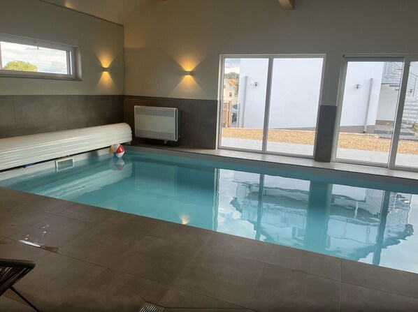 An indoor swimming pool with a view of the outside.
