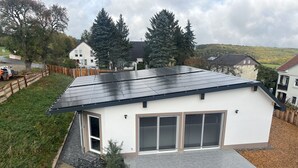 A modern house with a solar panel roof, a garage, and a well-maintained garden.