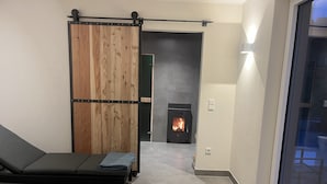 Ein modernes Zimmer mit einer Couch, einer Holzwand, einem Kamin und einem großen Fenster.