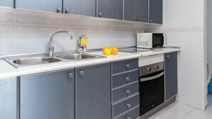 Een moderne keuken met grijze kastjes, een roestvrijstalen spoelbak, een magnetron en een inbouwoven.