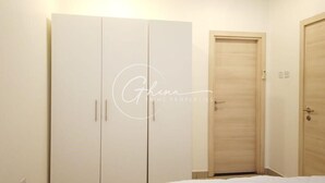 A bedroom with a wardrobe, a door, and a bed. - Luxury 2 Bedroom- The Gallery A32 (Accra)