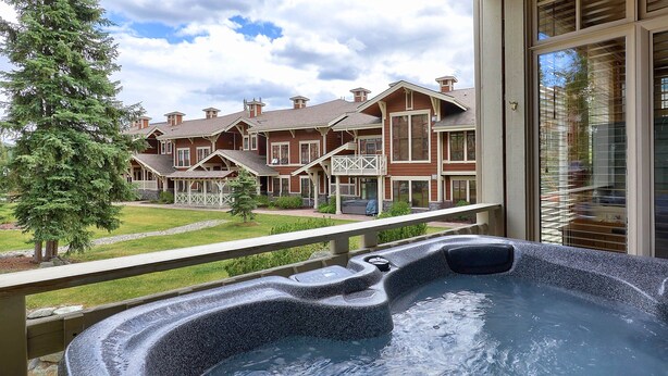 A hot tub on a balcony with a view of a row of brick houses. - Outdoor Adventure at Sun Peaks 33 (Sun Peaks)