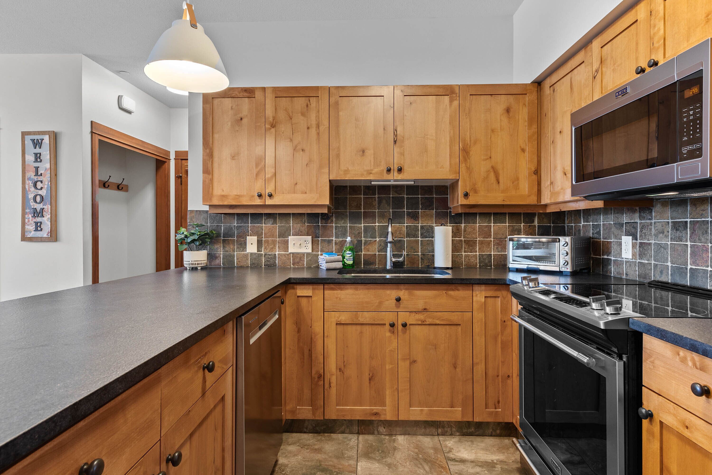 A kitchen with wooden cabinets, a microwave, a toaster, and a dishwasher.