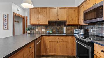 A kitchen with wooden cabinets, a microwave, a toaster, and a dishwasher.