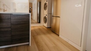 Una cuina moderna amb armaris de fusta, rentadora integrada i frigorífic.