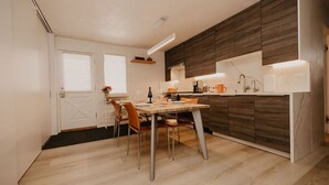 Cuina moderna amb una paret d'accent de fusta, zona de dinar amb taula i caires, i forn integrat.