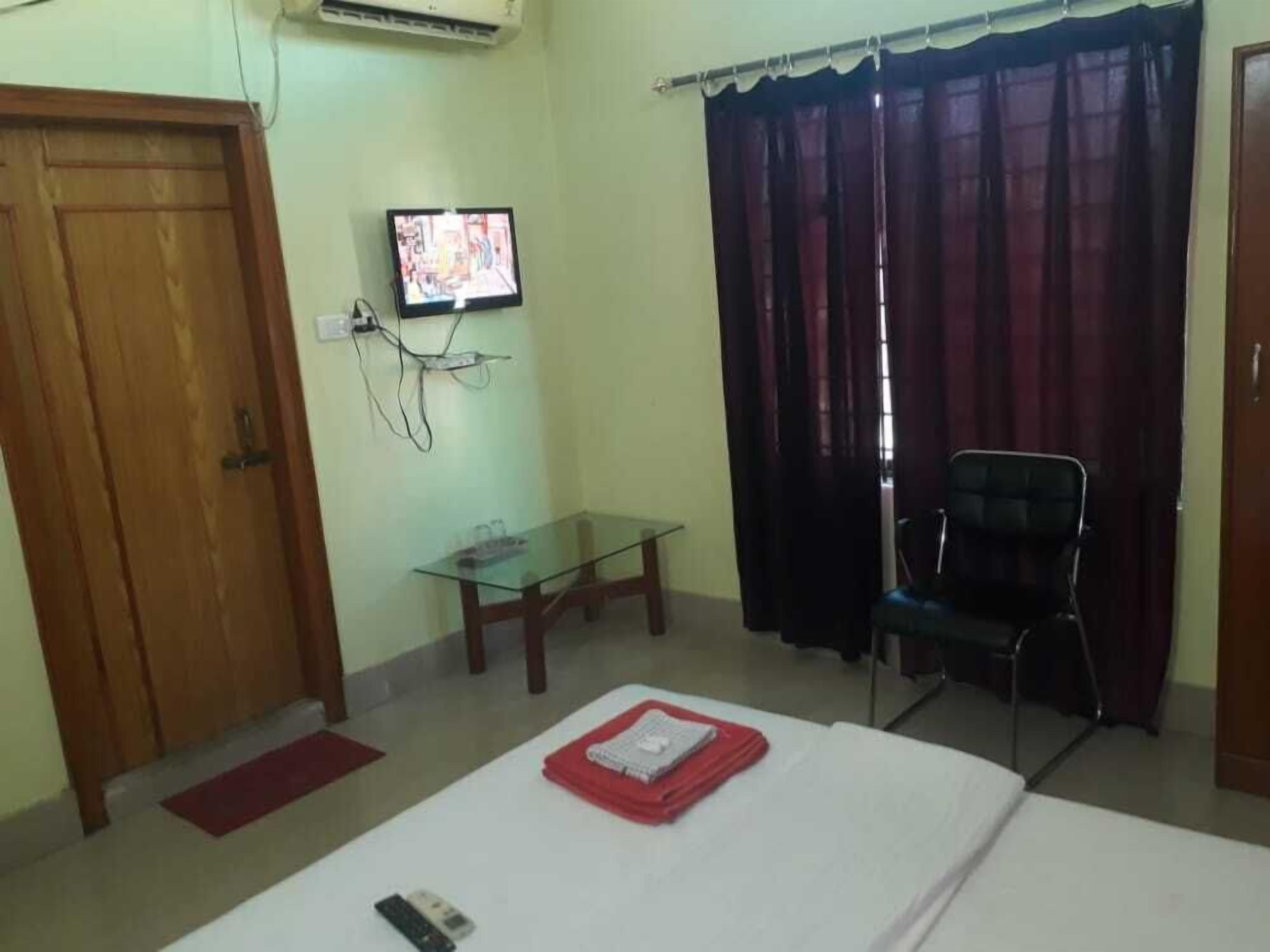 Une chambre d’hôtel équipée d’un lit, d’un bureau, d’une chaise, d’une télévision et d’une fenêtre avec des rideaux.