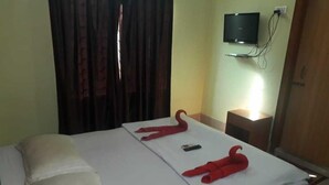 Una camera d'albergo con un letto, una TV a parete e una tenda.