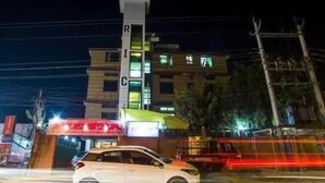 Un edificio a più piani con insegne illuminate e un'auto parcheggiata davanti.