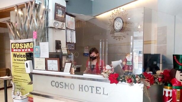A reception desk at the COSMO HOTEL with a clock, framed pictures, and a decorative garland. - Cosmo Hotel Espana Near Ust (Manila)