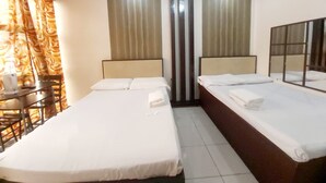 A hotel room with two beds, a small table with chairs, and a window with curtains. - Cosmo Hotel Espana Near Ust (Manila)