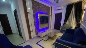 Ein modernes Wohnzimmer mit an einer Ziegelwand montiertem Fernseher, blauen Sofas und einem Couchtisch.