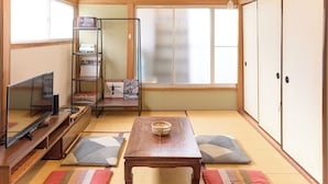 Et traditionelt japansk rum med tatamimåtter, fjernsyn, et træbord og en reol.