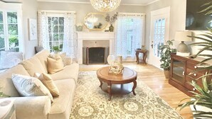 A spacious living room with a fireplace, a chandelier, and a television. - A Renovated Historical Home in PNW Monteith District (Albany)