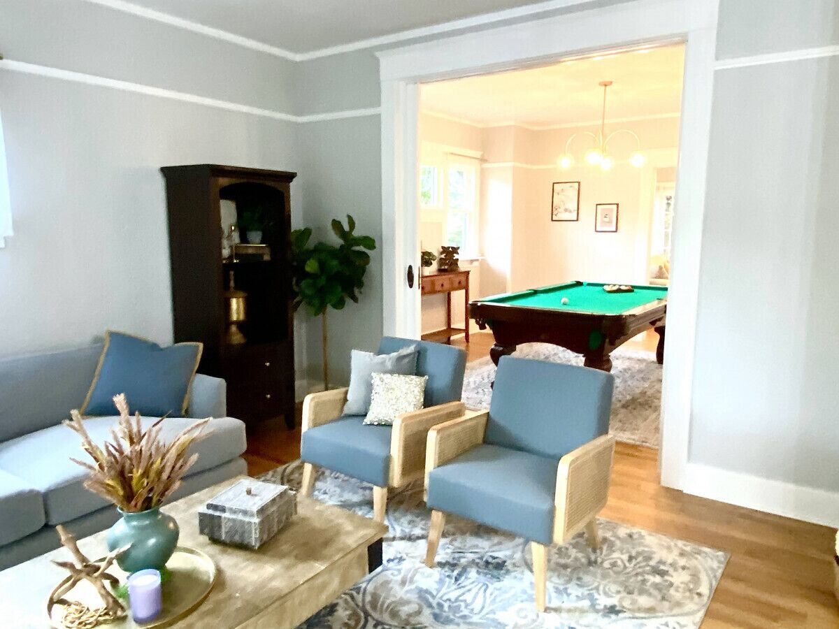 Ein Wohnzimmer mit Poolbillard, zwei Sesseln, einer Couch und einem Couchtisch.