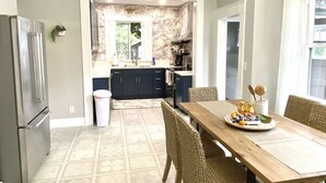 A modern kitchen with a dining area, featuring a built-in oven, a refrigerator, and a dining table with chairs. - A Renovated Historical Home in PNW Monteith District (Albany)