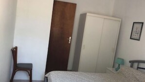 A bedroom with a bed, a wardrobe, a chair, and a door. - Ground floor in villa (L'Île-Rousse)