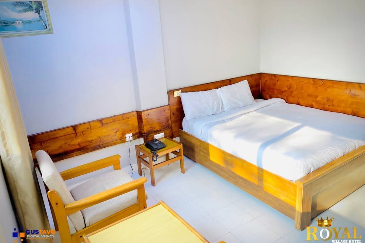 A single bedroom with a wooden bed, a small bedside table, a chair, and a nightstand.
