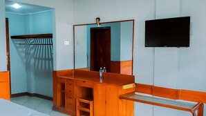 A hotel room with a bed, a wooden bench, a vanity with a mirror, a television mounted on the wall, and a door leading to a corridor. - Royal Village Hotel Dar Es Salaam (Dar es Salaam)