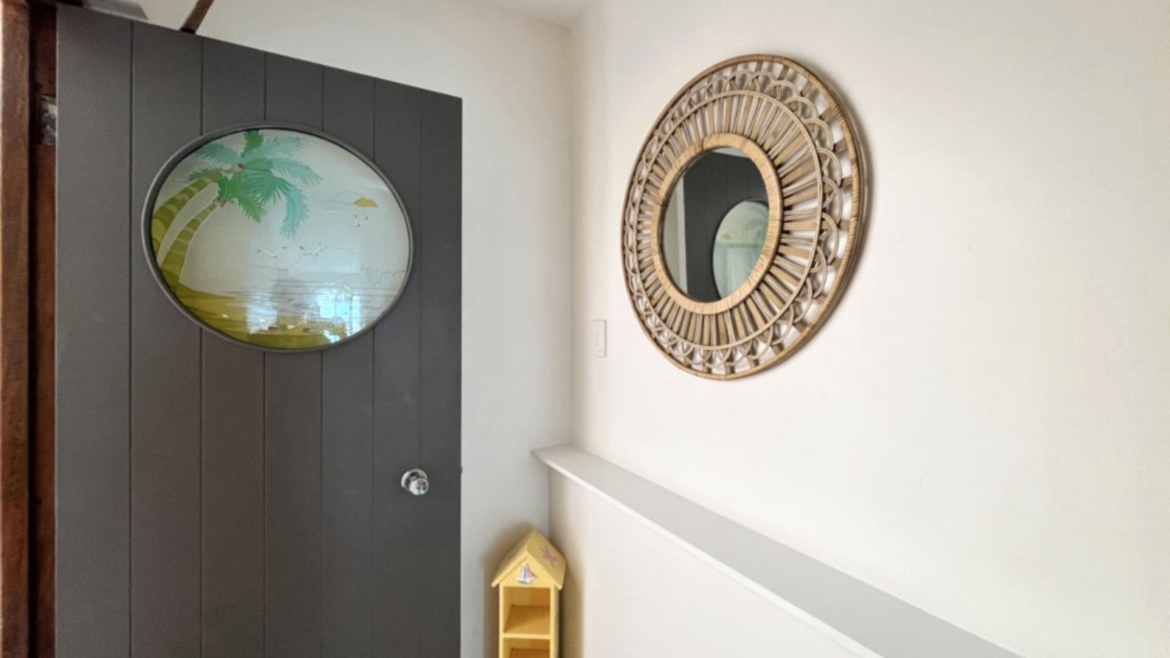 A door with a circular mirror and a small wooden house decoration.