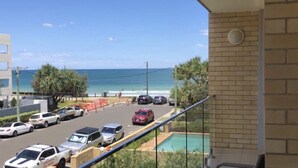 A balcony with a view of a beach and parking lot.