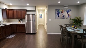Una cocina moderna con armarios de madera, un refrigerador de acero inoxidable y un comedor con mesa y sillas.