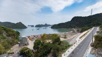 A coastal road with a view of the sea and hills.