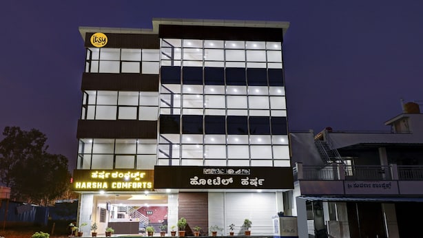 Um edifício de vários andares com uma placa indicando 'Harsha Comforts' no nível da rua.