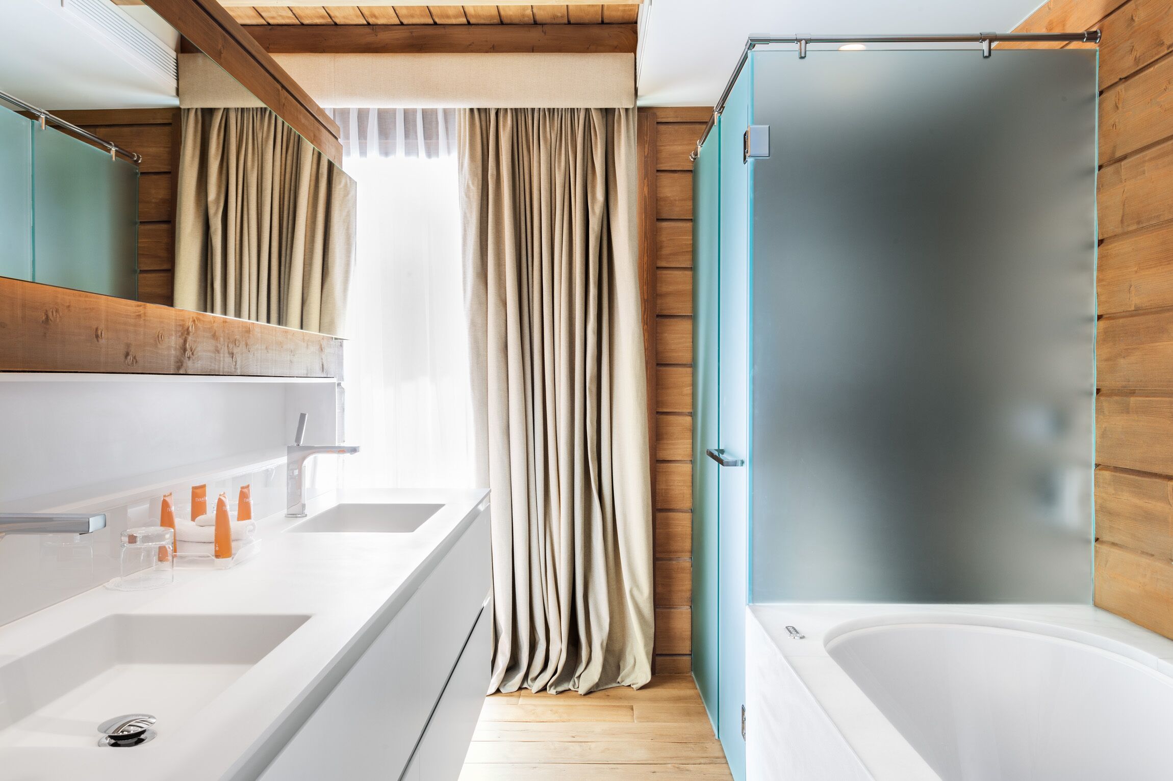Un baño moderno con detalles de madera, un espejo grande, una bañera y una ducha.