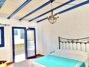Ein Schlafzimmer mit Bett, einer Kristallleuchter, einer Tür und Blick durch die Tür.