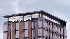 Un hôtel moderne, reconnaissable à son enseigne bien visible où l’on peut lire « DIVARES HOTEL ».