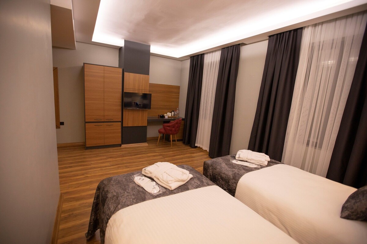 Habitación de hotel con dos camas, un armario de madera, un escritorio pequeño y una televisión.