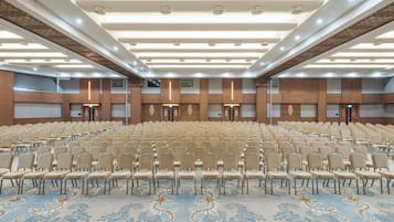 A large conference room with rows of chairs, a patterned carpet, and wooden paneling on the walls.