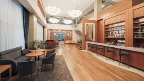 Een moderne hotel lobby met een bar, zithoek en trap.