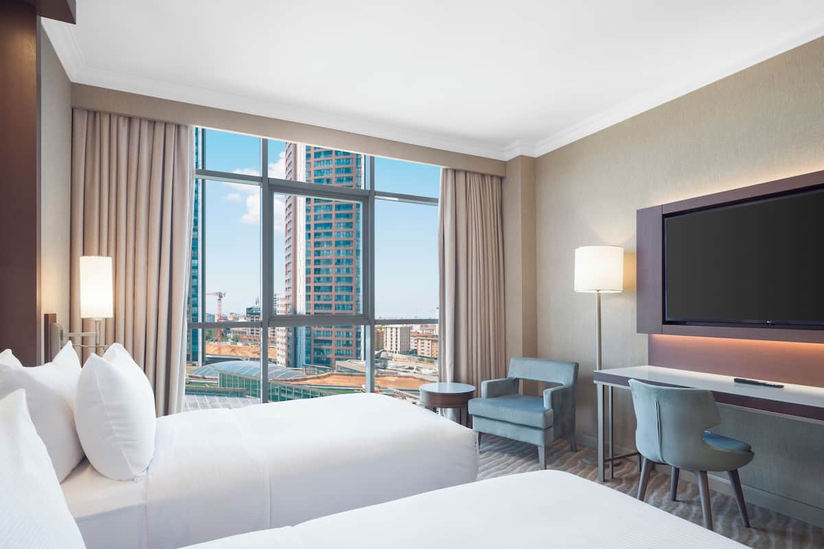 A hotel room with a large bed, two armchairs, a desk, and a TV.