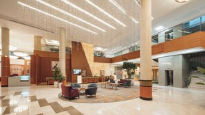 Een ruime lobby met een hoge plafond, moderne verlichting en een centraal gelegen zitgedeelte.