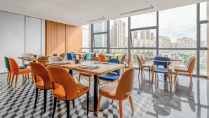A modern dining area with high ceilings and large windows offering city views. Tables are arranged with colorful chairs. - Holiday Inn Express Kunming Panlong by IHG (Kunming)