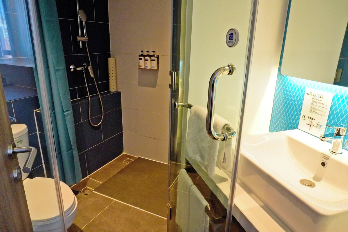 A modern bathroom with a glass shower enclosure, a white sink, and a toilet.