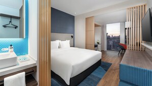 A modern hotel room with a large bed, a desk with a chair, a TV, and a view of the cityscape. - Holiday Inn Express Kunming Panlong by IHG (Kunming)