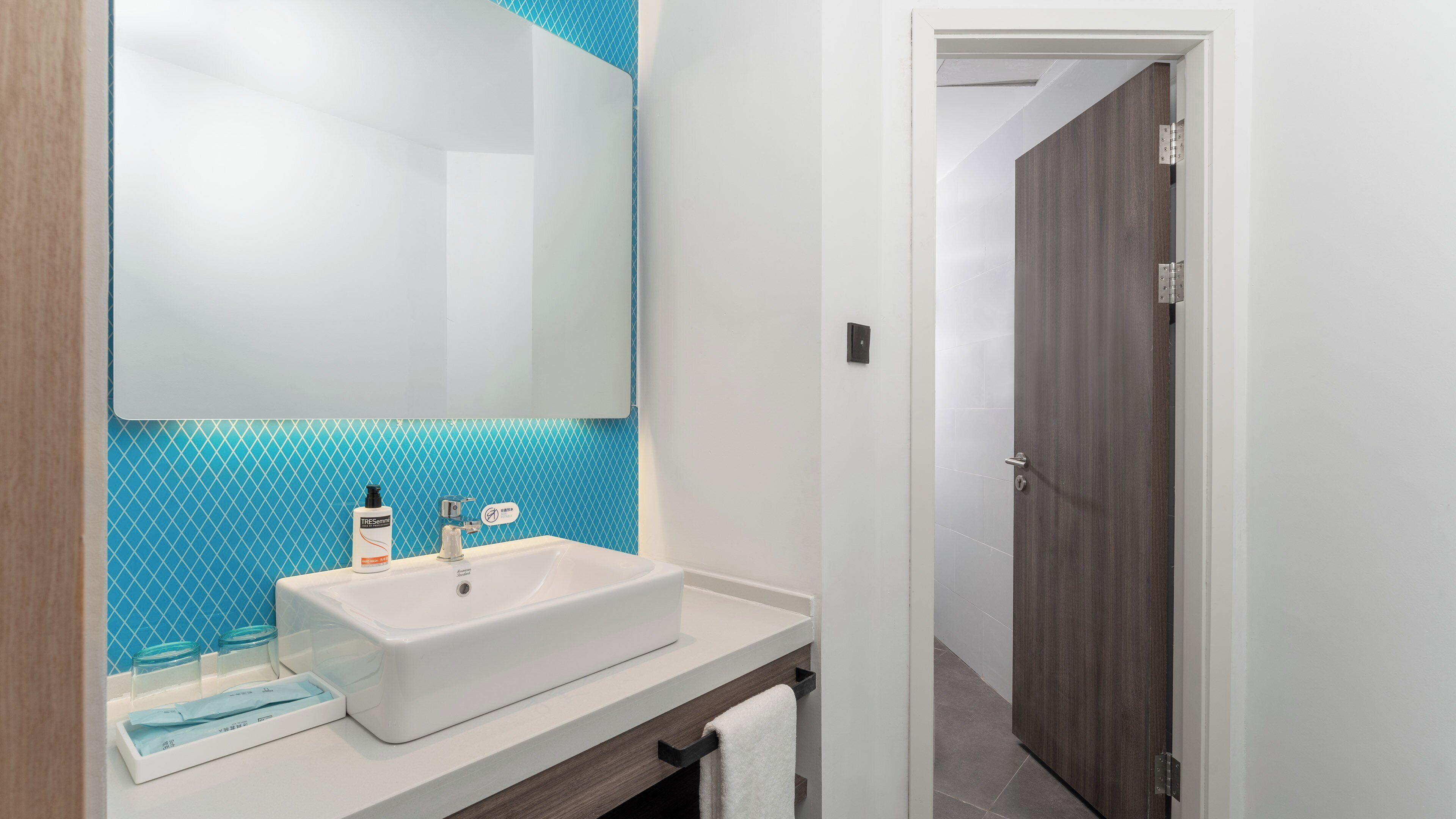 Une salle de bain avec un lavabo blanc, un miroir et un mur recouvert de carreaux bleus.