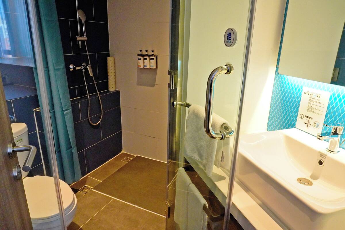 A modern bathroom with a glass shower enclosure, a white sink, and a toilet.