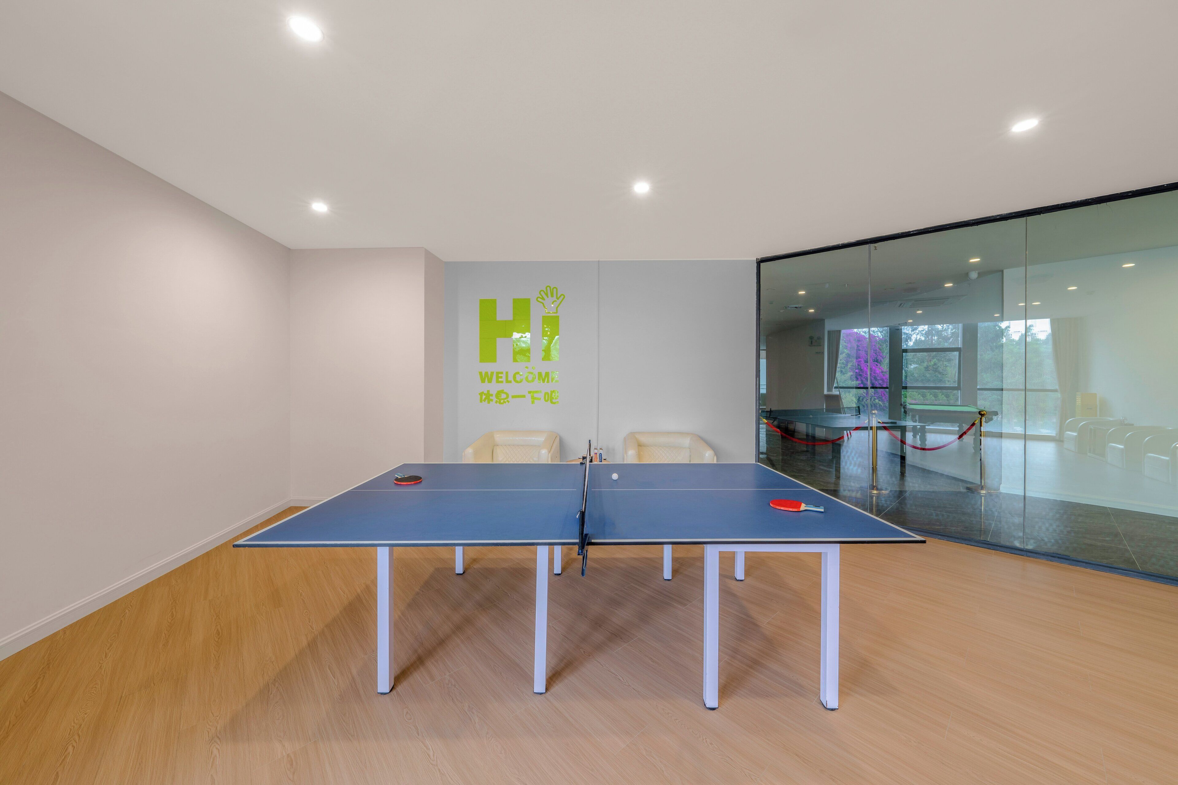 A conference room with a ping pong table, two chairs, and a glass partition.