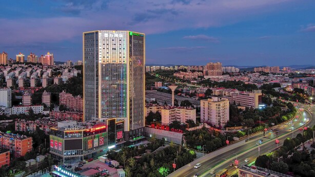 A high-rise hotel with a modern design, featuring a prominent vertical strip of windows and a rooftop terrace. - Holiday Inn Express Kunming Panlong by IHG (Kunming)