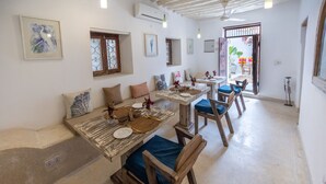 A dining area with rustic wooden tables and chairs, white walls, and artwork.