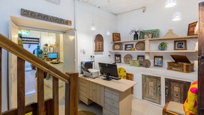 A home office with a desk, computer, and various decorative items on shelves.