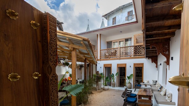 A courtyard with a wooden pergola, seating area, and potted plants.