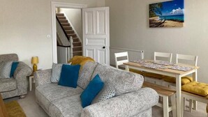 Uma sala de estar com sofá, mesa de jantar e um quadro na parede.