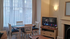Un salon comprenant une table à manger, des chaises, un téléviseur et une cheminée.